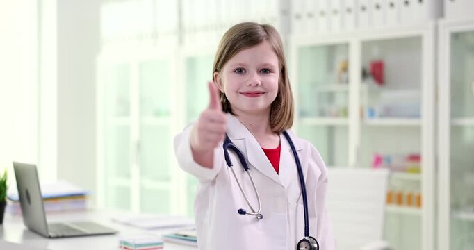 A young girl dressed as a doctor shares a sunny smile and gives a thumbs up in a bright, colorful pediatric clinic filled with toys and medical supplies.