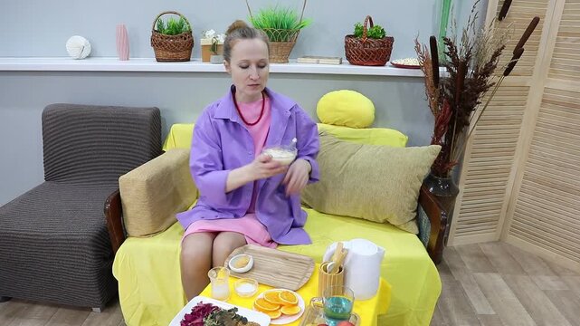 A woman eats cottage cheese with oranges and oat milk with a spoon