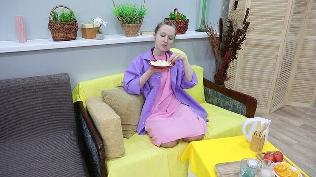 A woman finishes popcorn from a bowl and shakes off crumbs