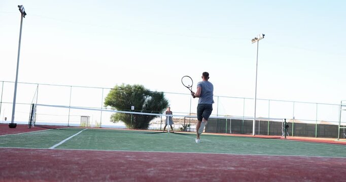 A player perfects their tennis skills on a court as the sun sets in the background. Each swing of the racket captures dedication and passion for the game.