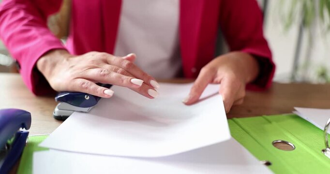 In a lively office filled with green accents, hands move elegantly to staple together bright white sheets of paper. The atmosphere buzzes with creativity and productivity.