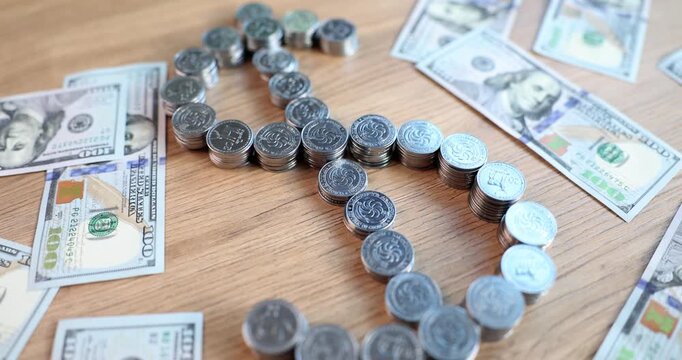 Coins and banknotes come together in a striking dollar sign display, resting on a smooth wooden table. This artistic piece captures the essence of currency and value in a unique way.