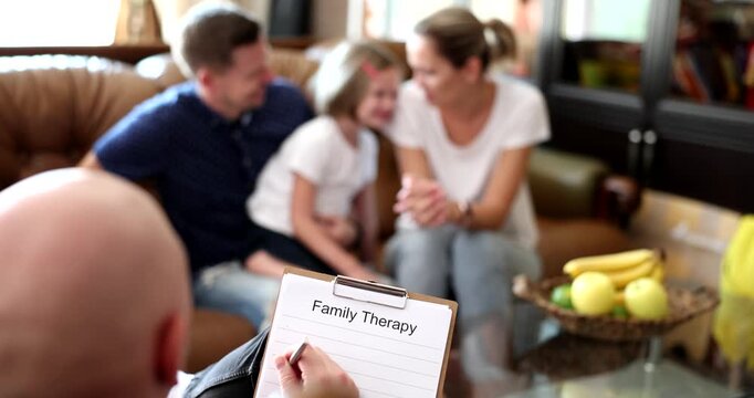 In a cozy living room, a family of three shares smiles and warmth during a therapy session. The atmosphere is supportive as they explore feelings together.