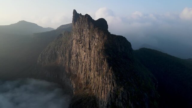 Aerial Drone Footage of Tebing Sumbing on Kelud Mountain Rising Above a Layer of Clouds in East Java, Indonesia. Dramatic Volcanic Cliff and Mountain Landscape Surrounded by Morning Cloudscape.
