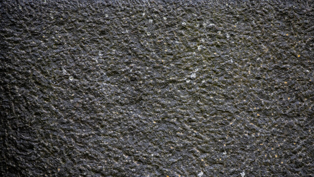 Dark grey rough stone surface texture background close up full frame