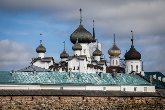 View of the historic Solovetsky Monastery with its iconic onion domes rising above ancient stone walls under a cloudy sky in Solovetsky, Arkhangelsk Oblast, Russia.