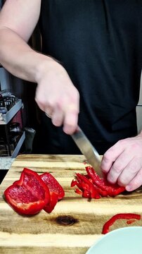 Man slicing fresh red pepper while preparing healthy real food meal at home