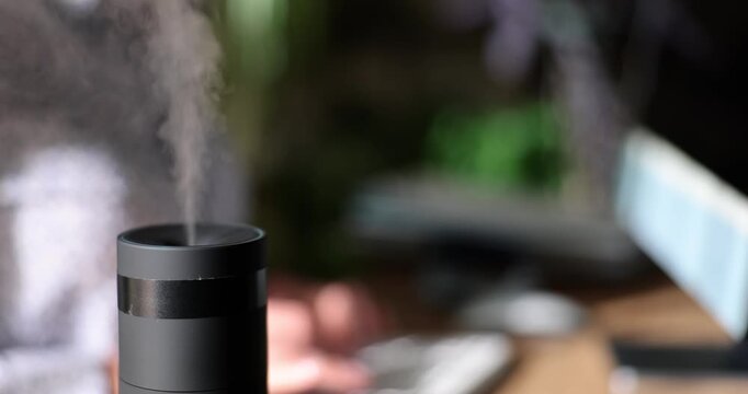 A soothing mist rises from a sleek diffuser in a tranquil workspace. Natural aromas fill the air as a relaxed atmosphere promotes focus and creativity.