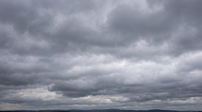 Expansive, soft grey overcast sky with subtle cloud formations stretching across the horizon, creating a calm.
