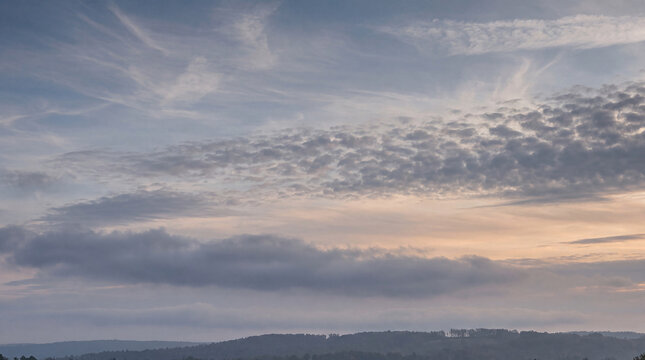 Overcast twilight sky featuring diverse cloud formations, including wispy cirrus and broken altocumulus.