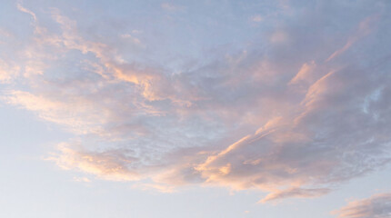 Delicate wispy cirrus clouds with soft pink and orange hues gracefully drifting across a pale blue sky. © Steven