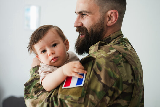 Male french soldier in military uniform hugs his little son at home - Emotional happy homecoming concept - Main focus on man face