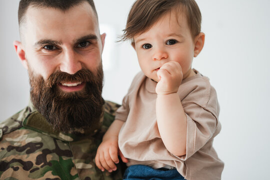 Male german soldier in military uniform hugs his little son at home - Emotional military happy homecoming concept - Soft focus on kid face
