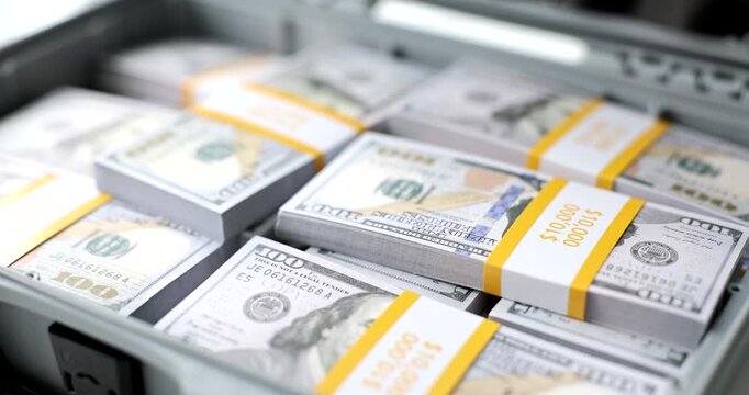 Bundles of cash neatly arranged in a sturdy case glow under the bright lights, showcasing the allure of wealth in a vibrant urban setting during the day.