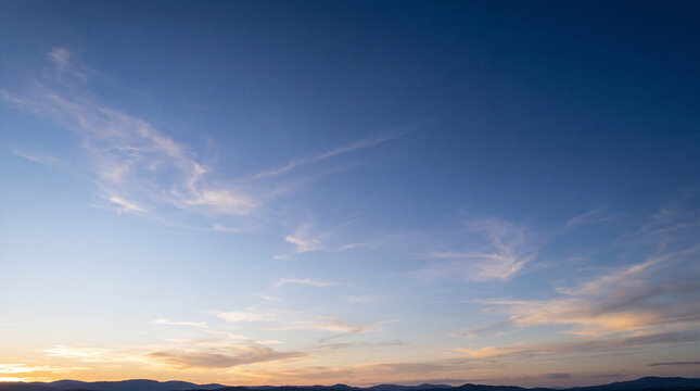 Picturesque clear blue sky with gentle wispy clouds at sunrise or sunset.