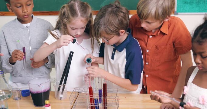 Diverse young children conduct a colorful chemistry experiment using test tubes and pipettes in a classroom.
