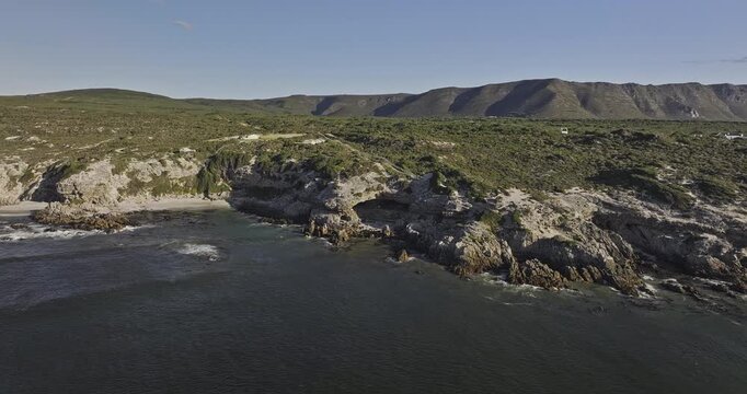 Gansbaai South Africa Aerial v30 low sunset flyover around Klipgat Caves, beach and De Kelders residences along the rocky shoreline - Shot with Mavic 3 Pro Cine - Jan 8th 2024