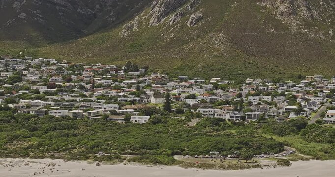 Hermanus South Africa Aerial v5 telephoto flyover above Grotto Beach residences on a green hillside beneath coastal mountains - Shot with Mavic 3 Pro Cine - Jan 8th 2024