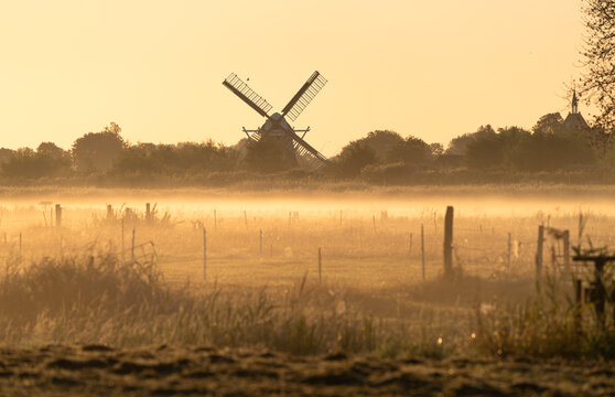A windmill on a foggy, summers morning in the Dutch countryside.
