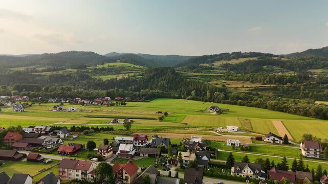 Aerial view of a village with houses and fields in a valley below forested hills in Czech Republic in summer