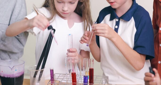 Diverse young children conduct a colorful chemistry experiment using test tubes and pipettes in a classroom.