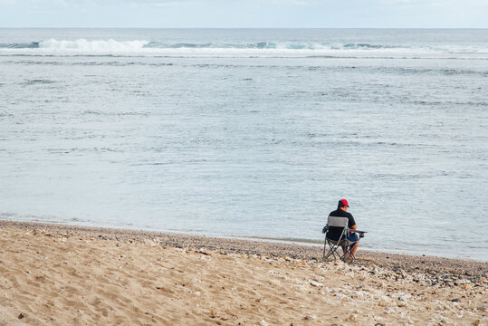 Une personne assise &agrave; la plage devant la mer regardant l'horizon.