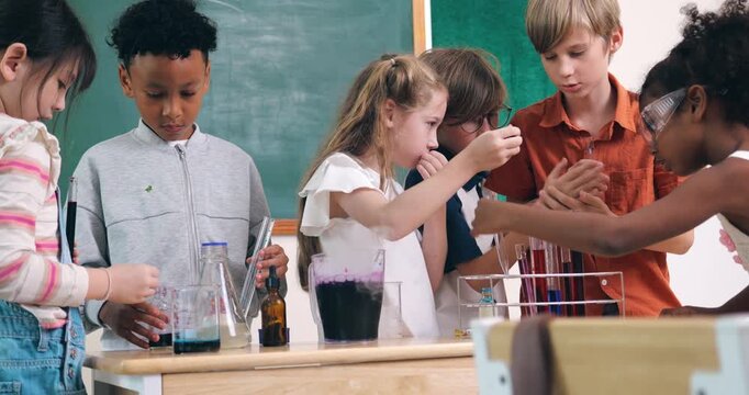 Diverse young children conduct a colorful chemistry experiment using test tubes and pipettes in a classroom.