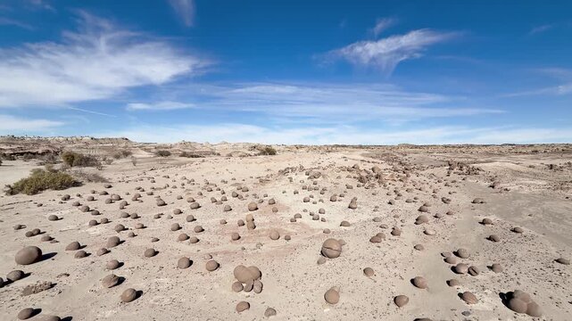 Cancha de Bochas in Ischigualasto Provincial Park, Valle de la Luna, San Juan, Argentina, featuring spherical sandstone concretions across an arid desert landscape beneath a blue sky, slow ya