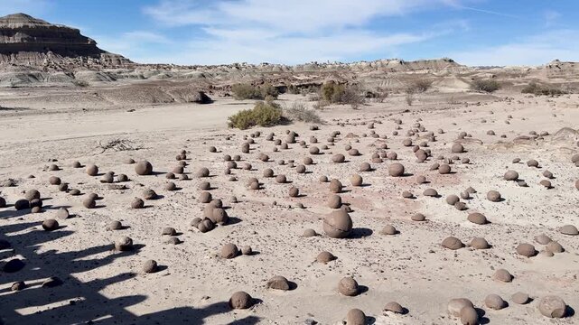 Cancha de Bochas in Ischigualasto Provincial Park, Valle de la Luna, San Juan, Argentina, featuring spherical sandstone concretions across an arid badlands landscape beneath a blue sky slow pan reveal