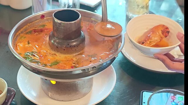 Hot and flavorful Tom Yum Goong, a famous Thai spicy shrimp soup, is freshly served and ready to enjoy.
