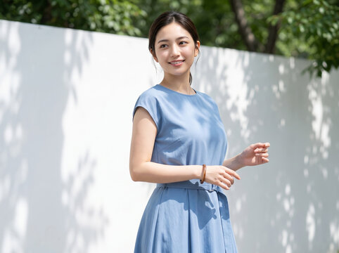白い外壁の前に立ち斜め前を見つめるドレス姿の女性