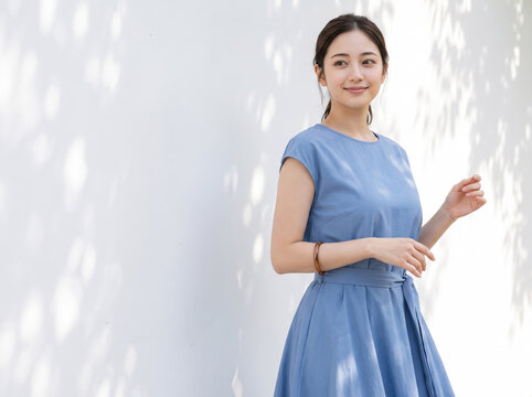 木漏れ日の中で微笑む青いワンピースを着た女性