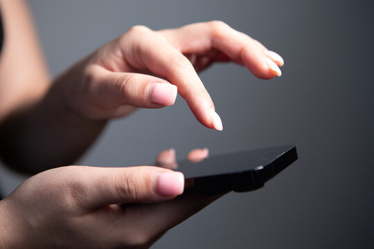 A young woman  holds a smartphone in her hands