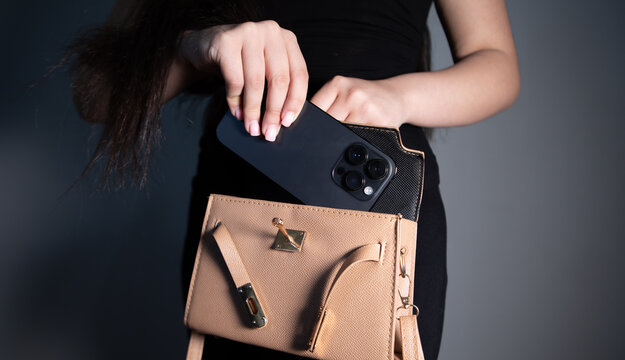Young woman putting mobile phone to her bag.