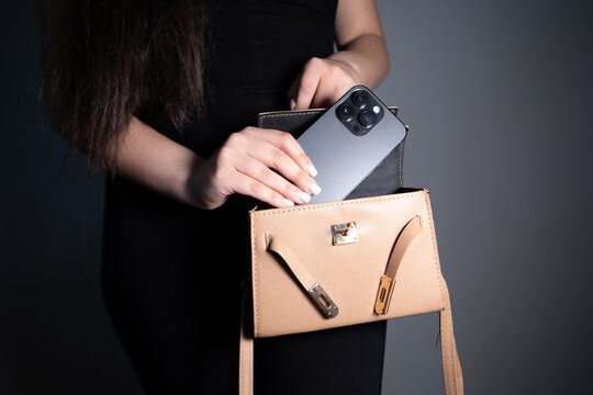Young woman putting mobile phone to her bag.