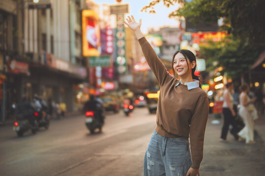Happy woman waving on Yaowarat Road in Bangkok Chinatown, enjoying urban travel and sightseeing in Thailand