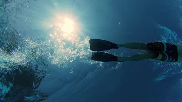 Underwater View of Man Swimming with Flippers Under Sun