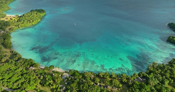 Aerial view of the turquoise waters of Port Resolution bay, surrounded by lush tropical vegetation and sandy beaches in Port Resolution, Tanna Island, Vanuatu.