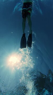 Underwater View of Man Swimming with Flippers Under Sun