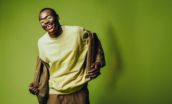 With a playful smile, the man poses for a stylish studio portrait