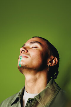 Man portrait in studio with green face paint and calm fashion style