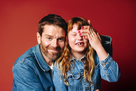 Father and daughter share a playful smiling family portrait together