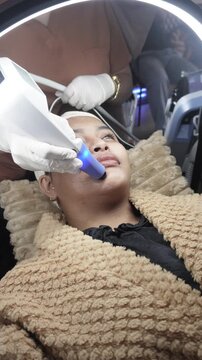 Female patient receiving dual radiofrequency and ultrasound facial treatment at an aesthetic clinic for skin tightening. Currently on forehead.