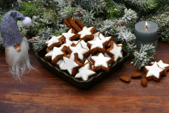 Bowl with cinnamon stars, cinnamon sticks, and almonds on a rustic wooden table.