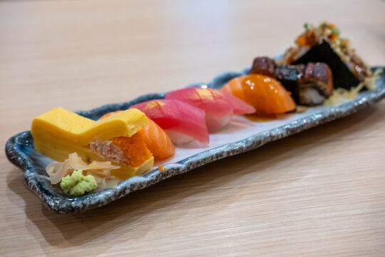 Assorted Japanese sushi arranged on a plate, including salmon, tuna, shrimp, tamago, ikura, and other colorful sushi varieties served with wasabi and pickled ginger.