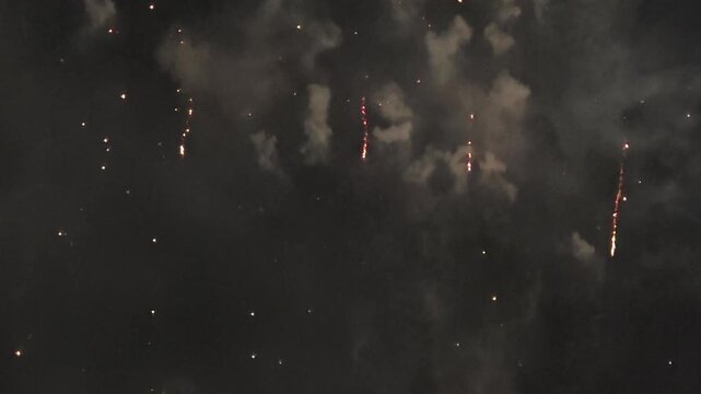 Firework streaks trailing in dark night sky