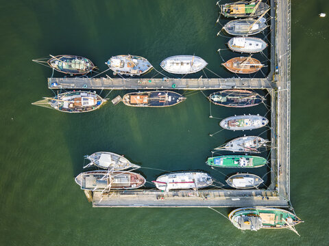 Aerial view of Klippan with various boats moored at the wooden pier in the calm green water of the harbor in Goteborg, Vastra Gotalands lan, Sweden.