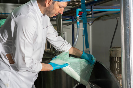 Man pouring Flour In Mixing Machine in industrial factory. Middle-aged manager with expertise