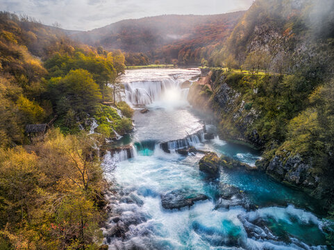 Aerial view of Strbacki buk waterfall cascading over rocks surrounded by vibrant autumn foliage and lush forest in Orasac, Federation of Bosnia and Herzegovina, Bosnia and Herzegovina.