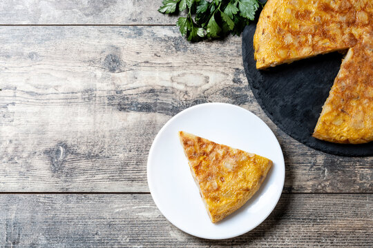 Slice of Traditional Spanish Potato Omelette on wooden table. Top view. Copy space